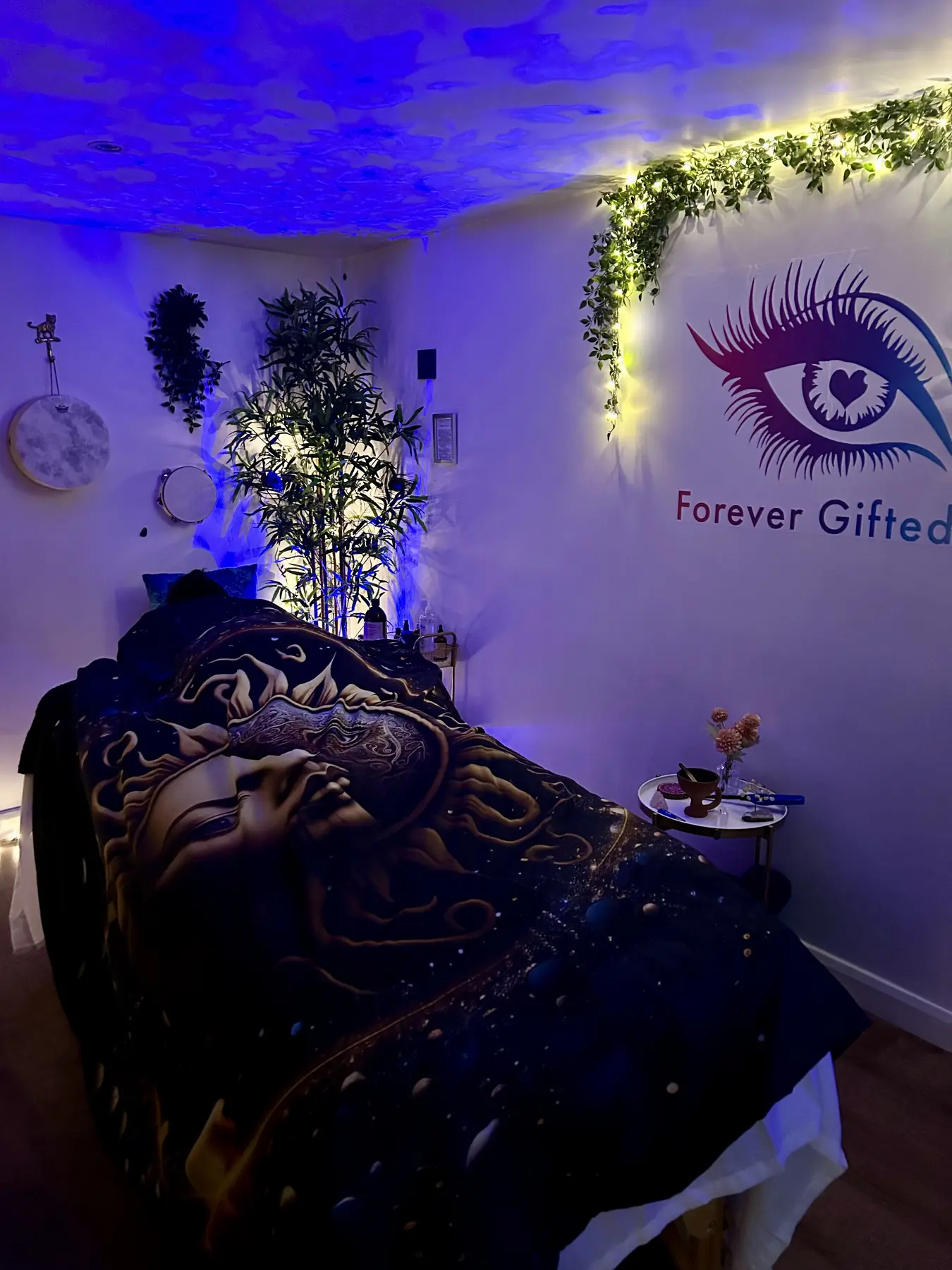 The cabin under soft blue light with the treatment bed and the eye on the wall