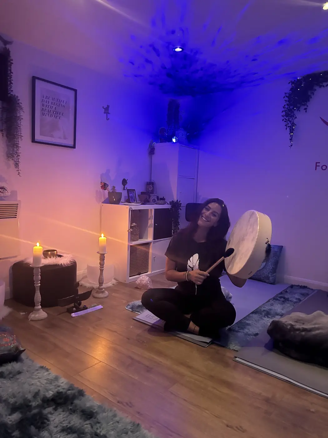 Filiz sitting cross-legged on the cabin floor with Otis and a beater, candles lit behind her